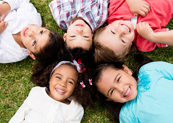 Aerial photograph looking down at a group of five children laying on their backs in a circle