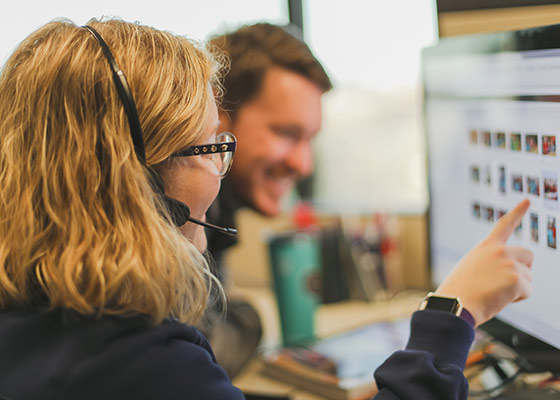 a man and woman with headsets on working on a computer