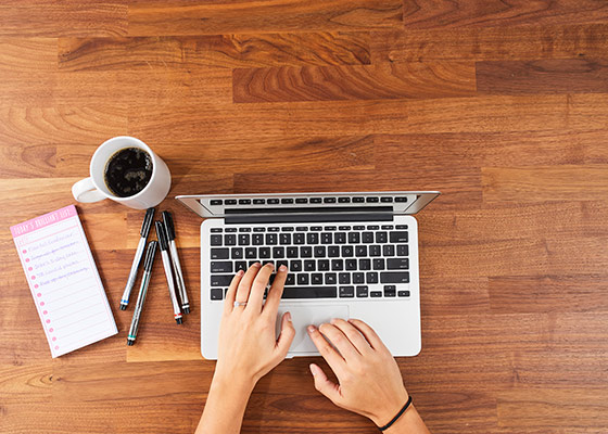 aerial image of laptop, coffee, pens and paper