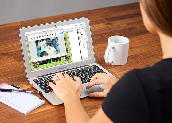 looking over the shoulder of a woman using the photo editor on her laptop