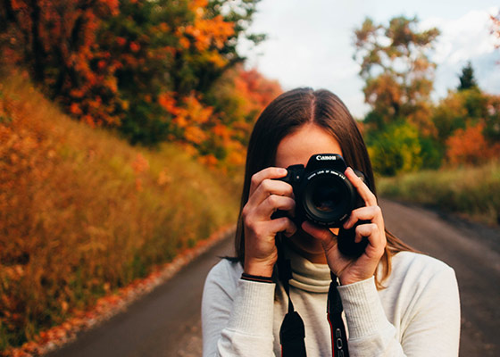 woman taking photo of fall trees changing colors