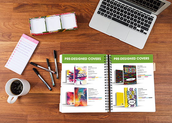creative-covers-and-themes25-26 Aerial picture looking at notes, coffee, pens, laptop, and open yearbook manual